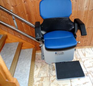 A stair lift with a blue seat next to stairs.