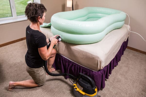 A woman is vacuuming the mattress with an air hose.