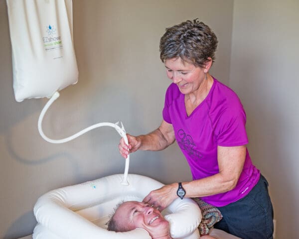 A woman is using an electric device to wash the baby.