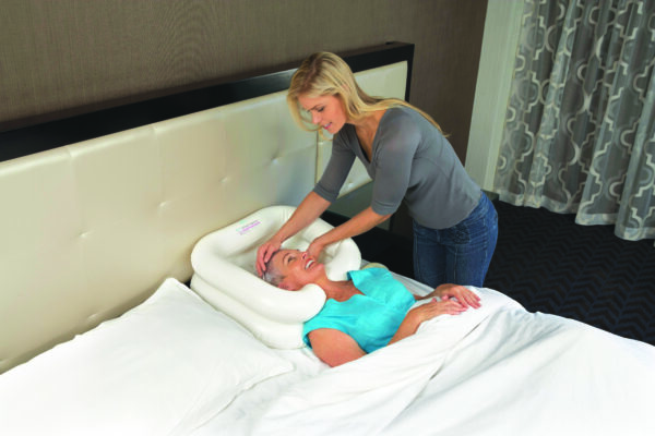 A woman is helping someone in bed with the inflatable bath tub.