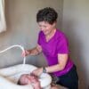 A woman is washing a baby in the tub