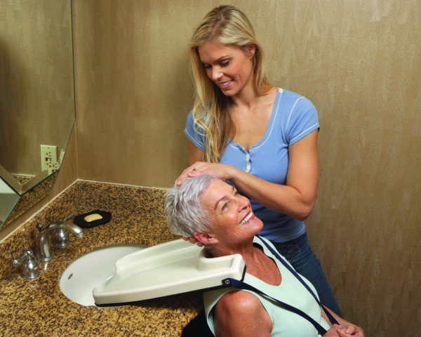 A woman is getting her hair combed by another woman.