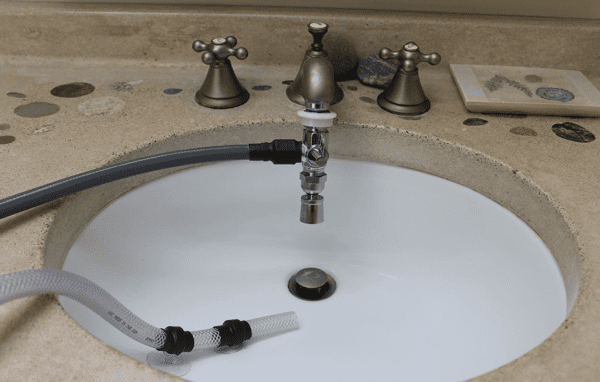 A sink with two faucets and a pipe in it.